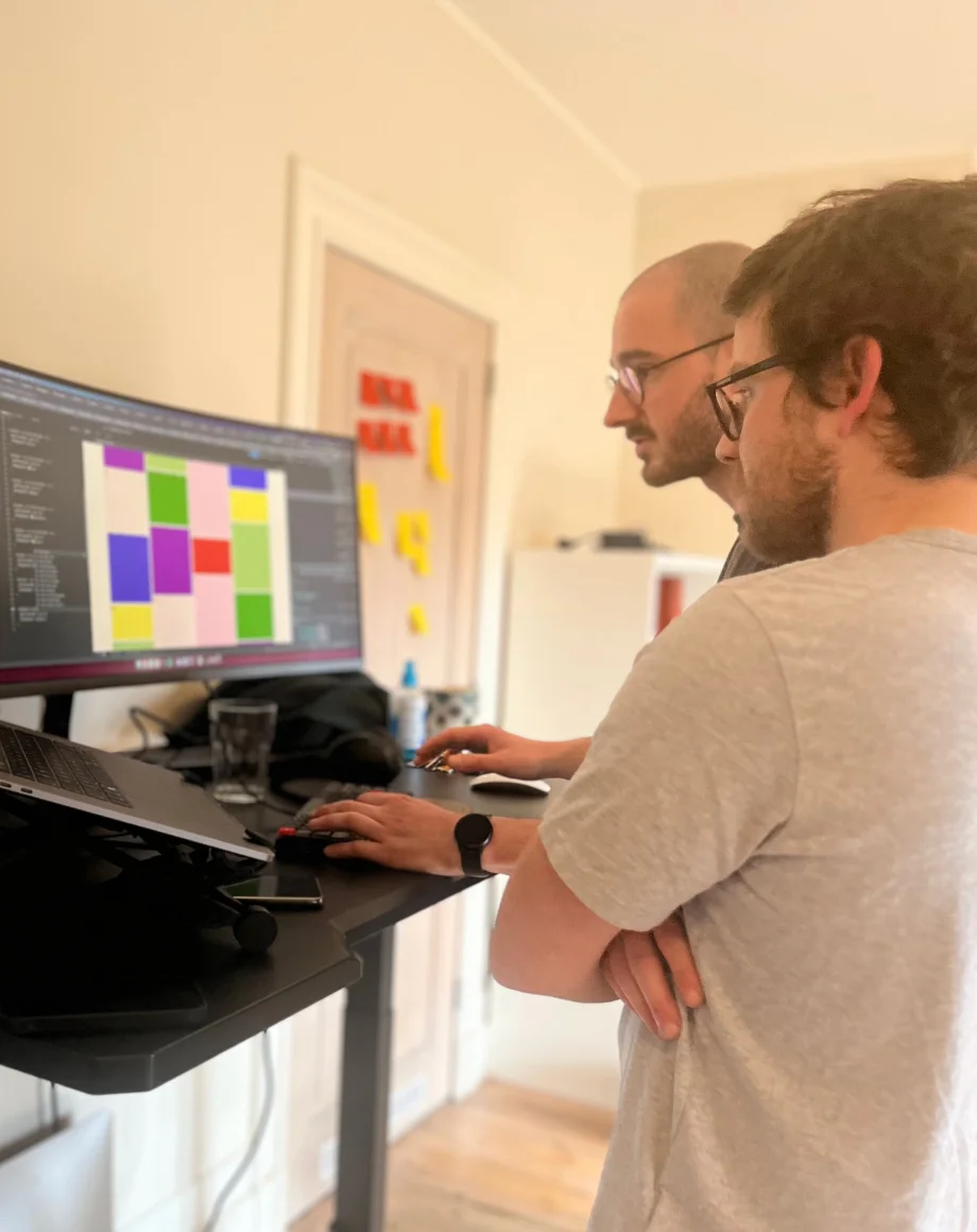 Two guys working at the standing desk looking at their screen