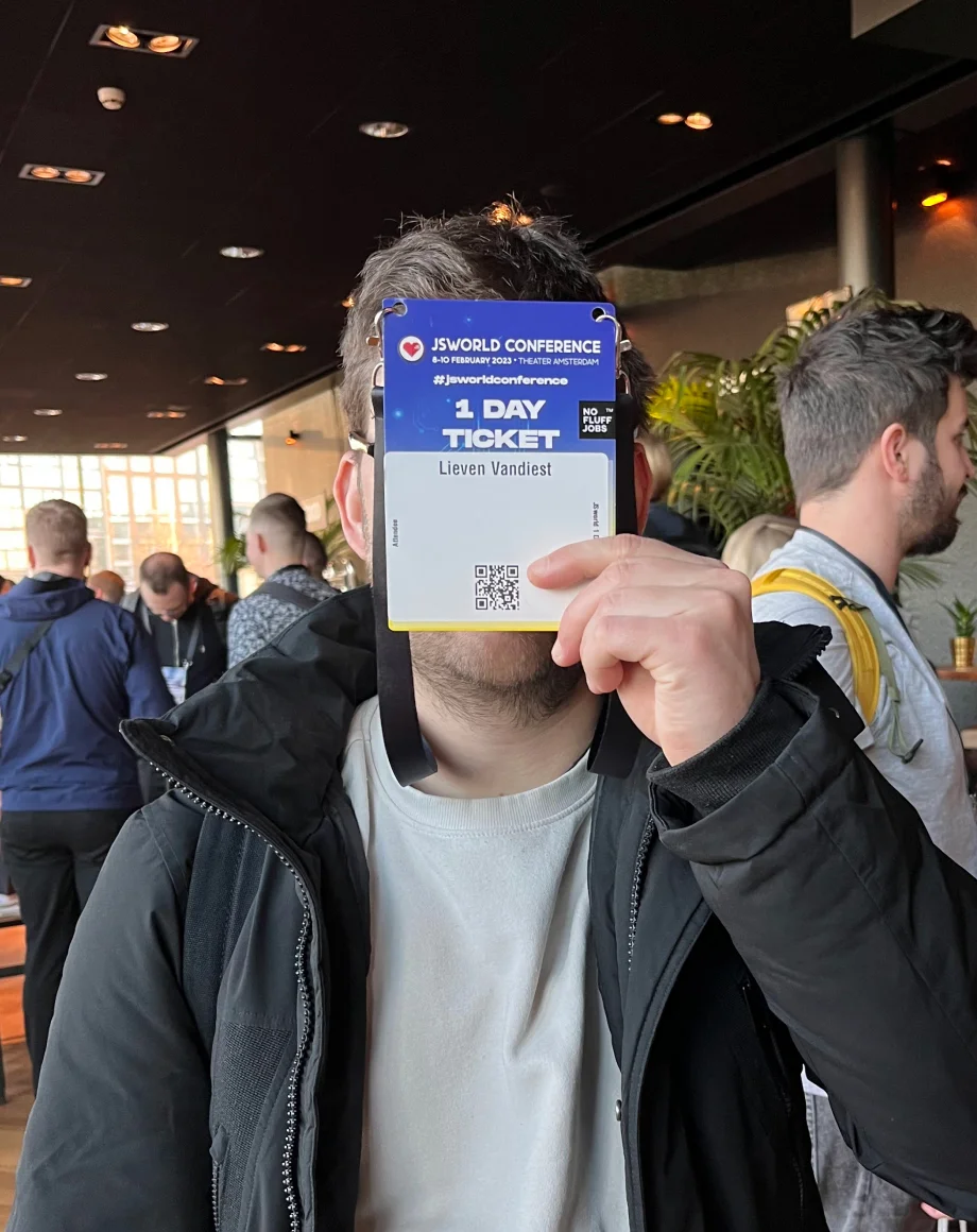 a guy at a conference, looking at the camera with the badge in front of his head